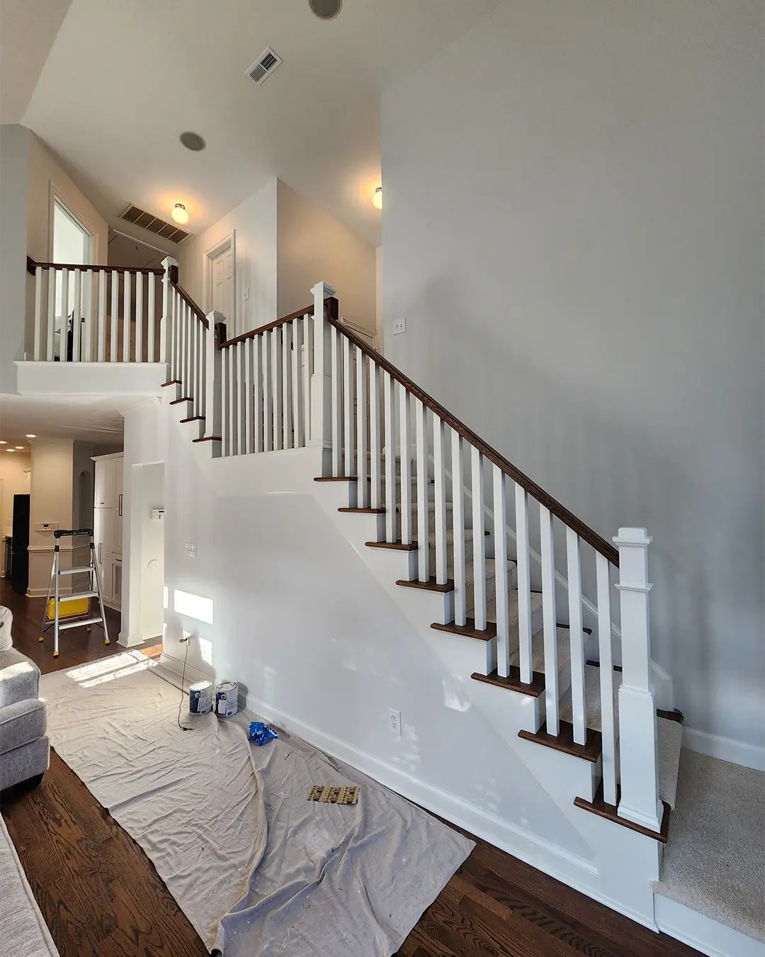 Freshly painted two-story stairwell with white trim and warm gray walls
