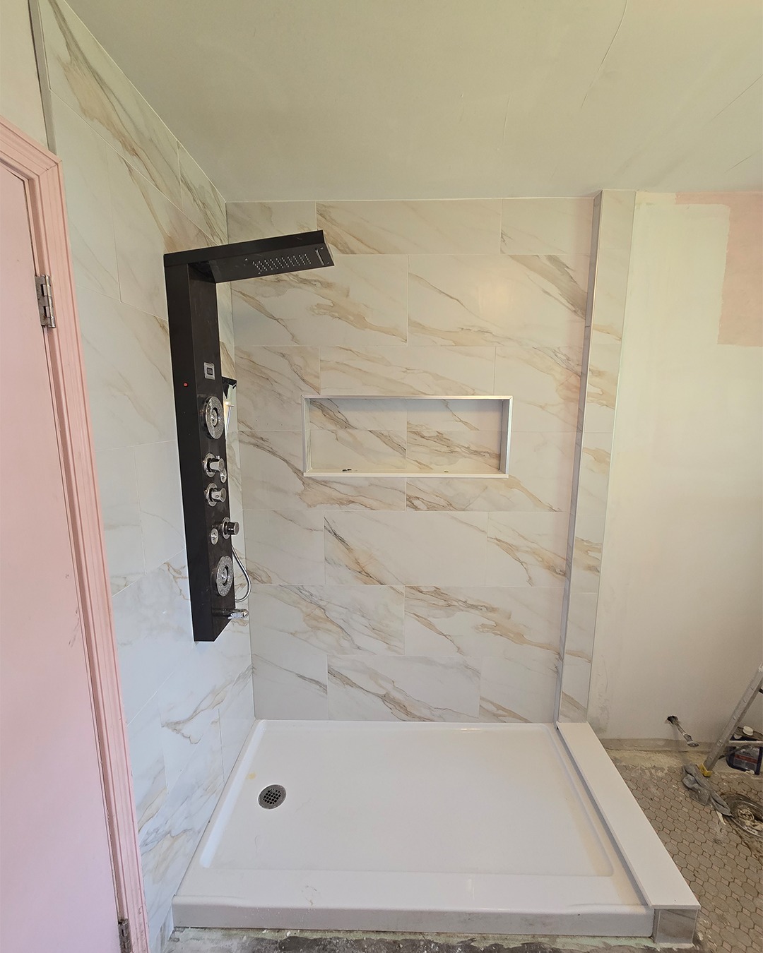 Modern shower with marble-patterned tile walls and a black luxury shower panel