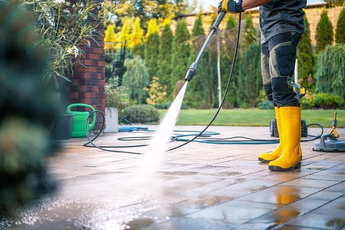 Professional pressure washing a paved patio with water spray